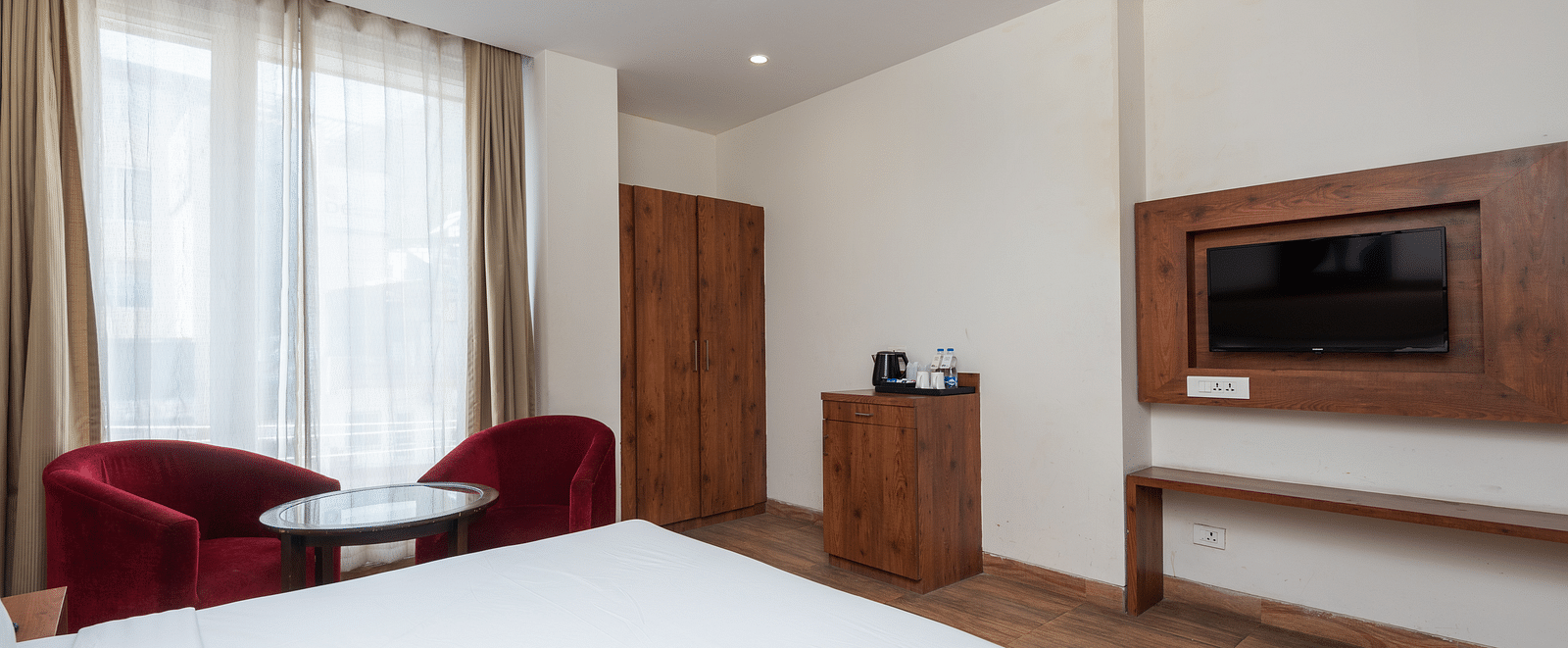 Premium room featuring a television, wooden wardrobe, a cosy table with two chairs at DLS The Classio